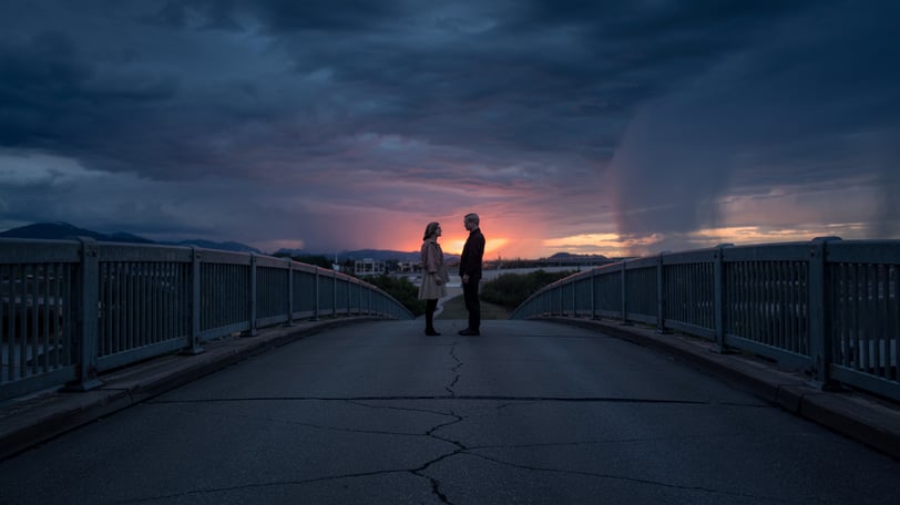 a couple standing on a bridge looking at each other