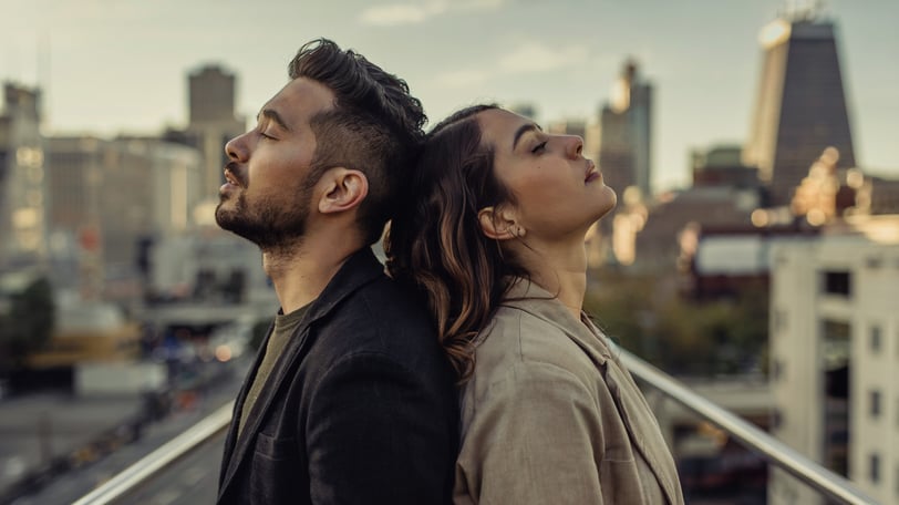 a man and woman standing on a balcony with a city view
