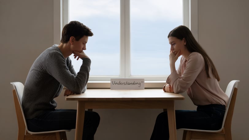 a man and woman sitting at a table with a laptop