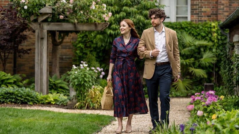 a man and woman walking down a path in a garden