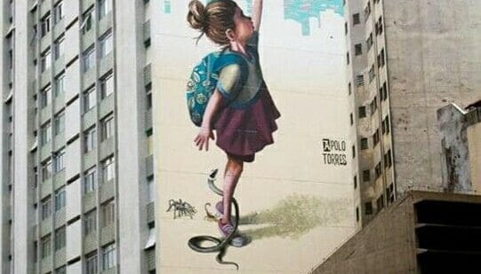 Detalhe de um mural de grafite mostrando rostos expressivos e cores vivas