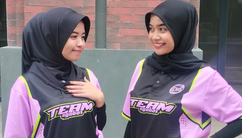 two women in hijab clothing standing next to each other