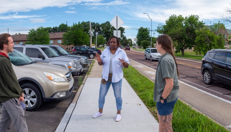 Sophia talking to two young people while standing on a sidewalk