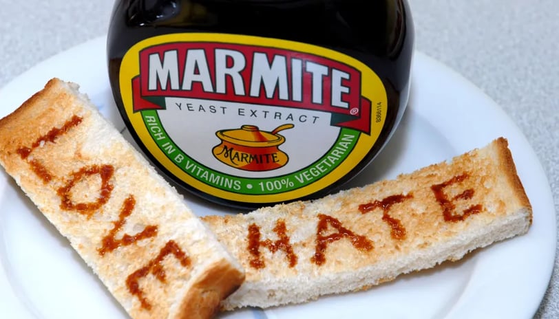 Jar of Marmite on a white plate with two soldiers that read love and hate
