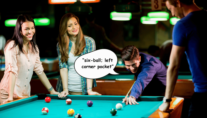 A group of friends smiling and playing a game of pool