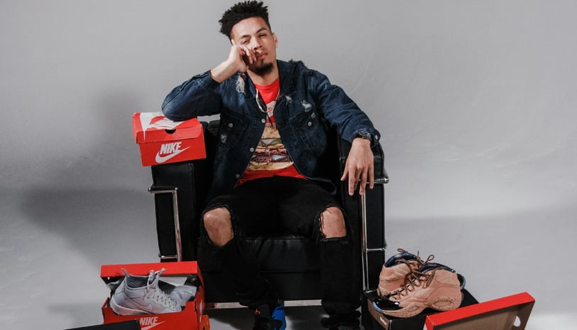 a man sitting in a chair with a shoebox and a shoebox of sneakers