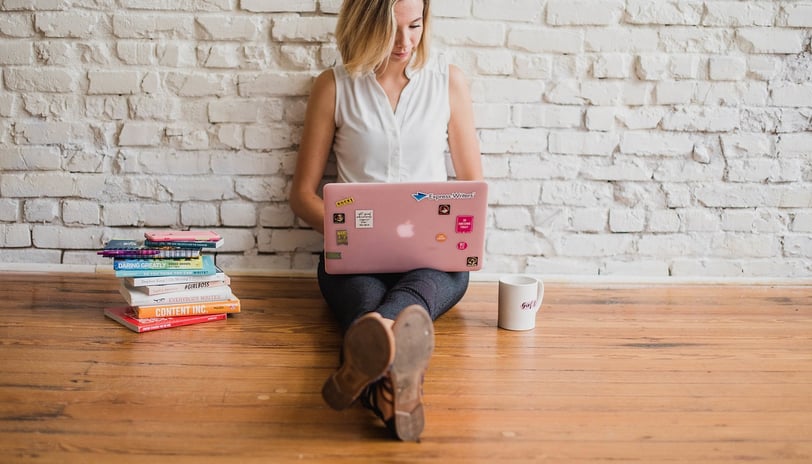 a woman sitting on a wooden floor with a laptop computer