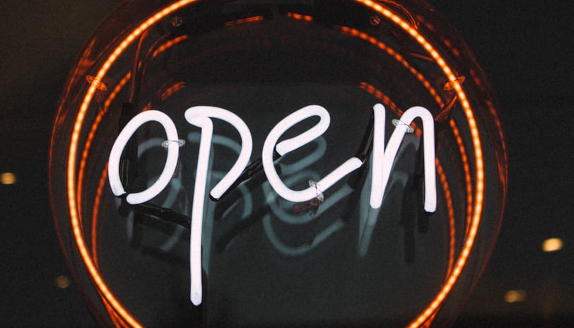 a neon sign that says open on the outside of a building