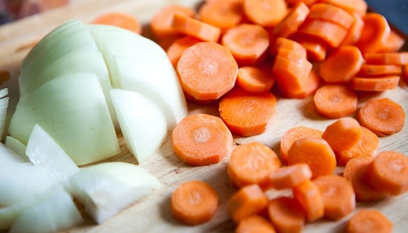 a cutting board with onions and carrots on it