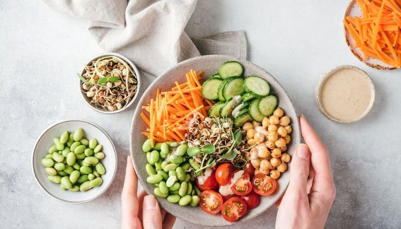 a person holding a bowl of food with vegetables