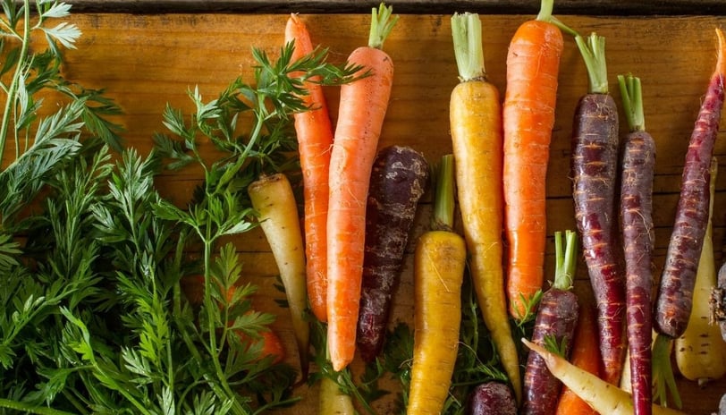 a bunch of colorful carrots are on a wooden table