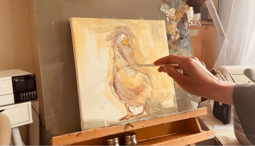Alex working on a painting on canvas of a duck