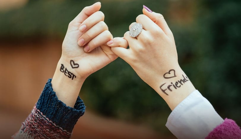 a woman's hand with "best" written on the wrist intertwined with another hand with "friends" written