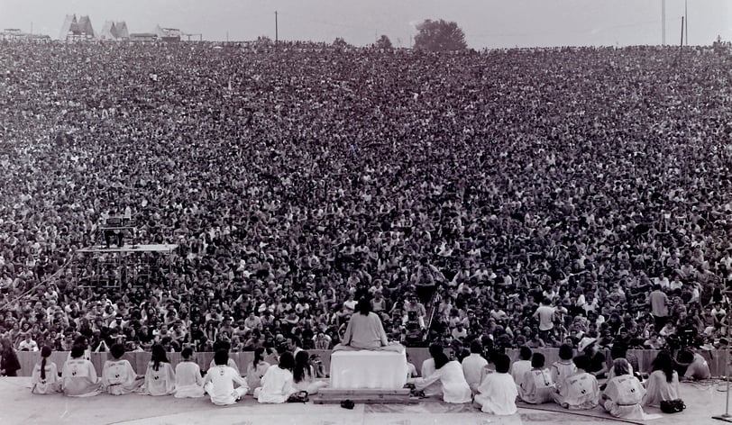 Swami Satchidananda on stage in front of a huge crowd as he opens the Woodstock Festival in 1969