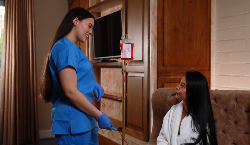 a nurse in scrubs providing IV therapy drip in a hotel