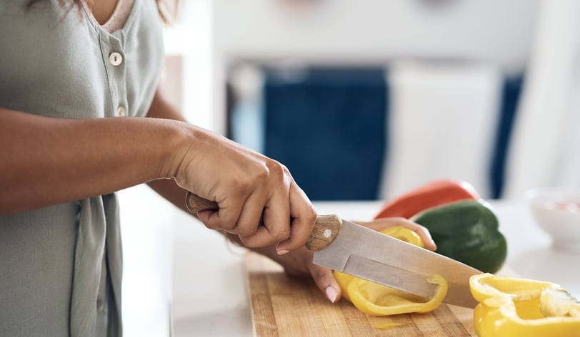 Woman cutting a bellpepper on a chopping board