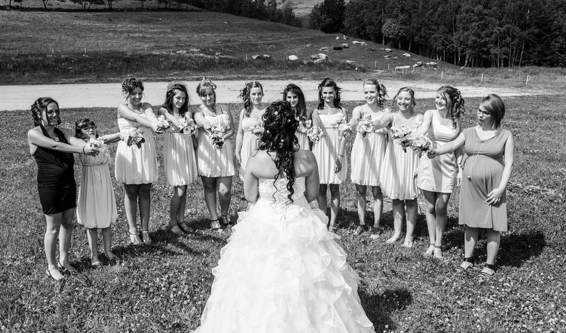Photo en noir et blanc des demoiselles d'honneur avec des bouquets autour de la mariée