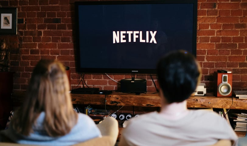 a man and woman sitting on a couch watching a tv