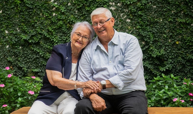 Reencuentro emotivo entre hermanos mayores, sentados juntos, sonriendo con alegría, celebrando su unión tras años de separaci