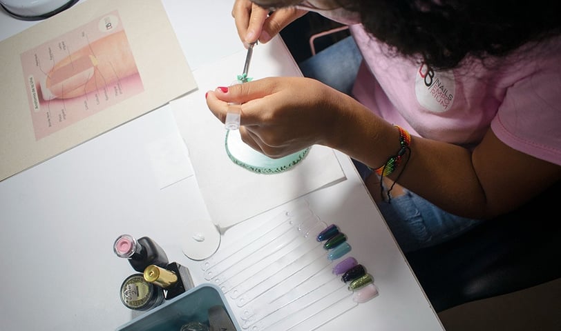 Vista cenital del curso de uñas acrílicas y semipermanentes para principiantes, mostrando herramientas y materiales.