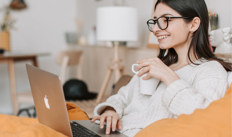 a woman sitting on a couch with a laptop and a cup of tea