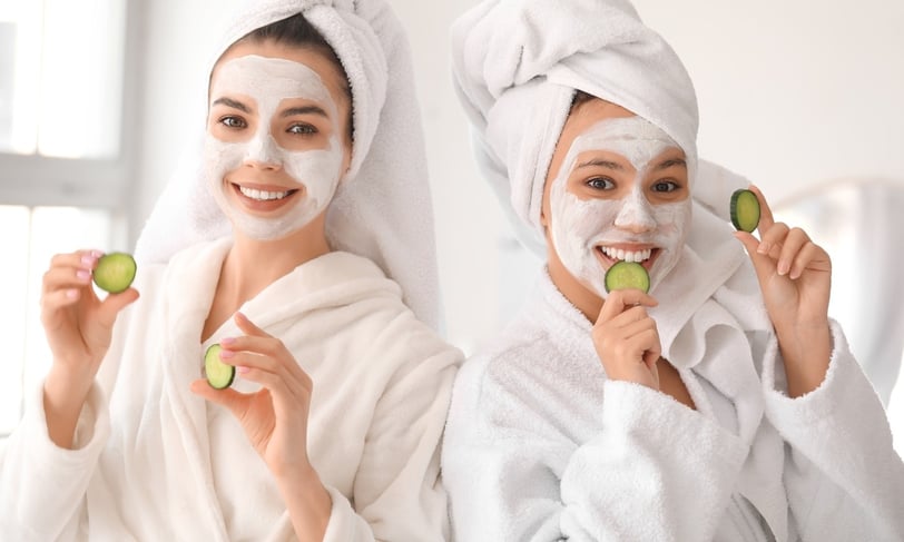 Two women with face masks and cucumber slices enjoying a spa day at home