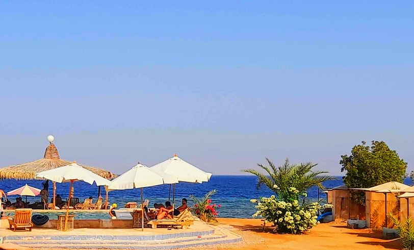 uma praia com guarda-sóis ao redor de uma piscina no Egito