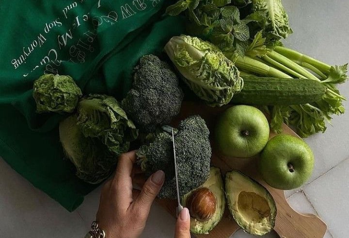 Pessoa cortando frutas e legumes mostrando qual é a dieta ideal para ter uma vida saudável 