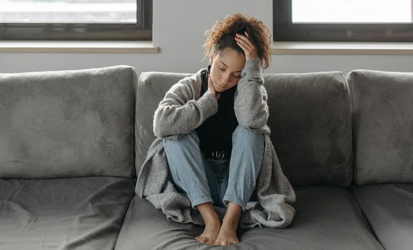 una mujer cansada en un sofá gris