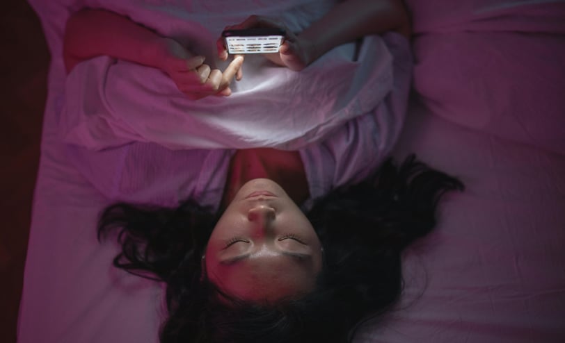 a woman laying on a bed with a cell phone