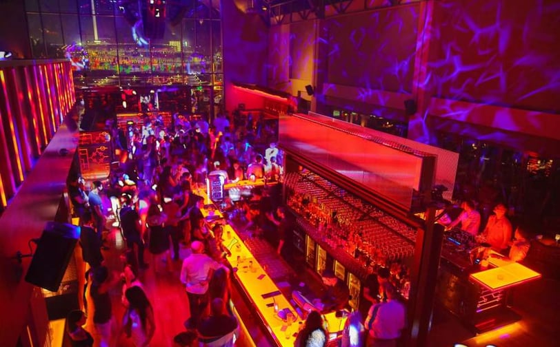 a crowded bar with people sitting at tables and drinking