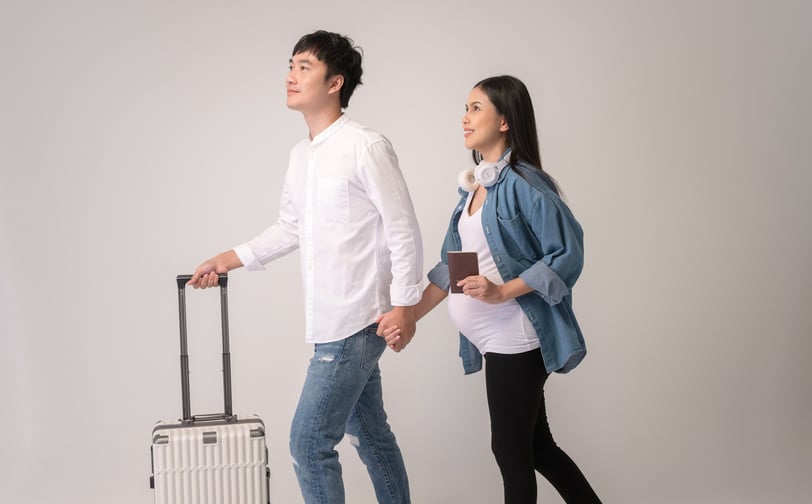 Pregnant couple with suitcase at airport