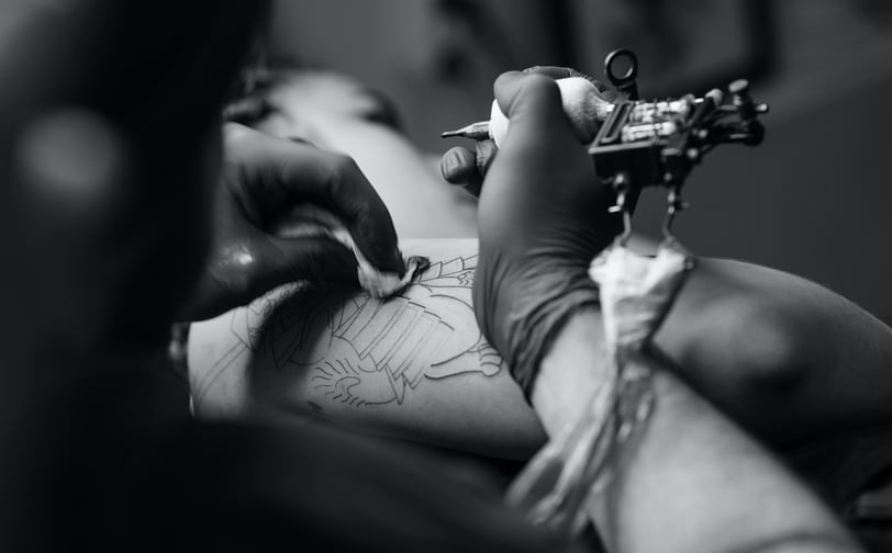 Artista tatuando um cliente com uma máquina de tatuagem.