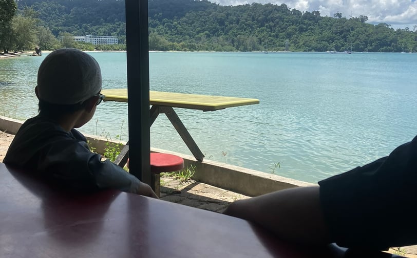 boy sitting at cafe overlooking ocean and mountain