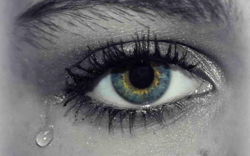 A tear is falling down from the eye of a woman