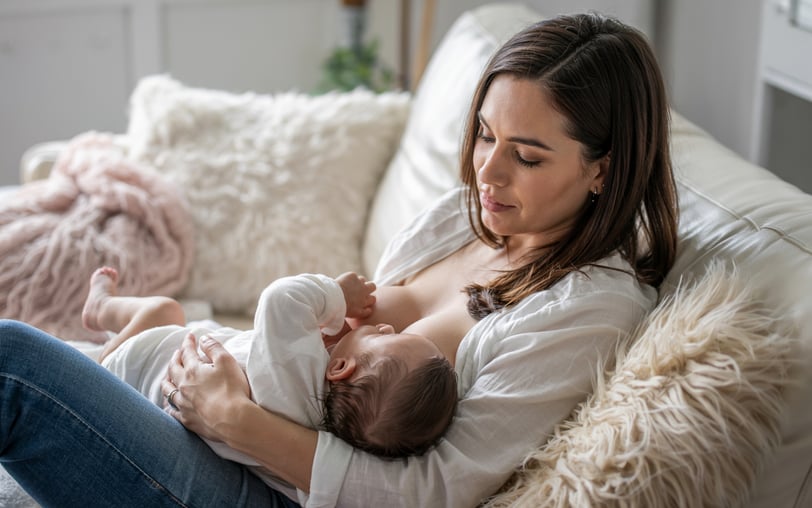 a woman breastfeeding a baby in a white shirt