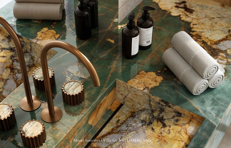 Close-up of a Green marble countertop with gold faucet and accessories in a modern bathroom.