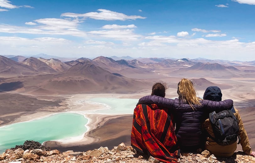 Three friends seen from behind facing Laguna Verde at the summit of Licancabur volcano.