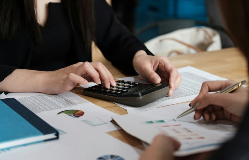 a woman is sitting at a desk with a calculator and graph charts