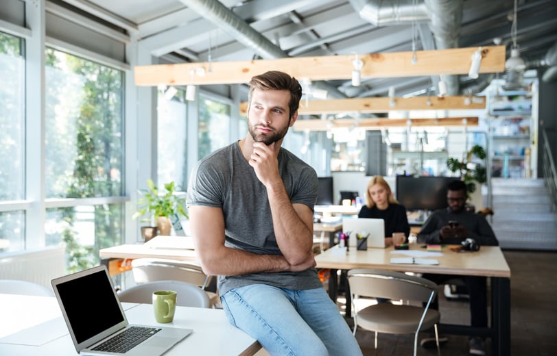 a man sitting at a table with an open laptop in an office