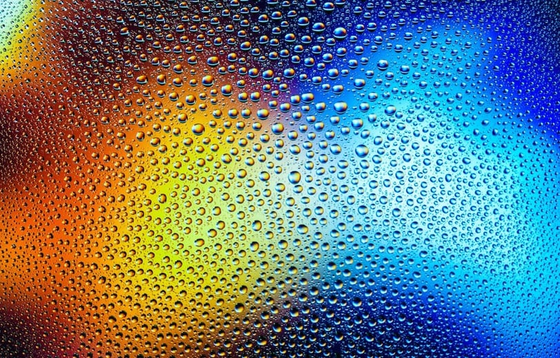 Yellow and blue lights behind rainy glass.