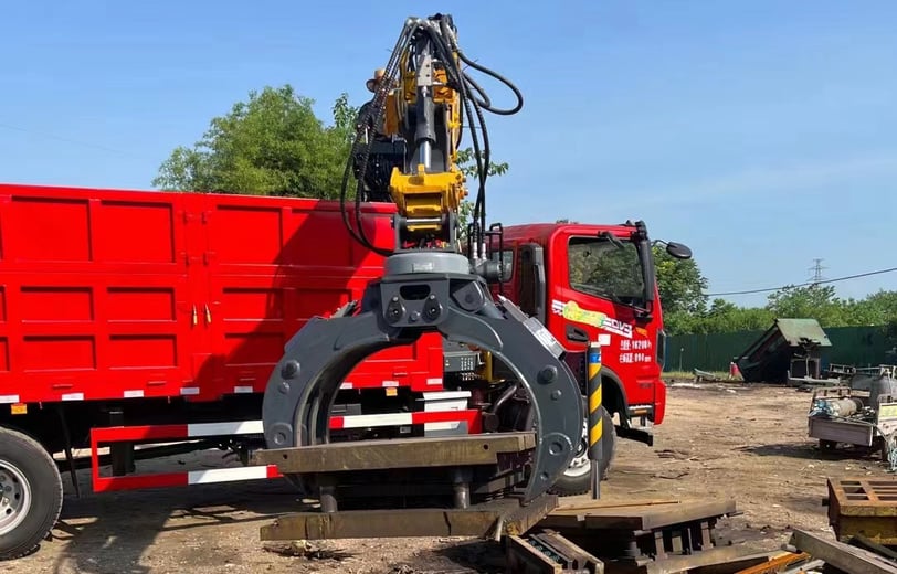 Red truck equipped with knuckle loader crane and gripper.