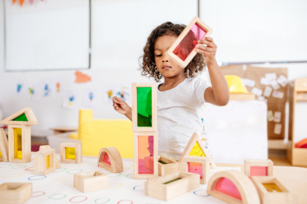 a young girl playing with wooden blocks in a classroom