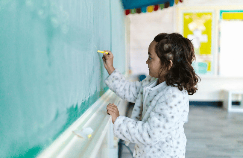 A girl writes on a chalkboard.