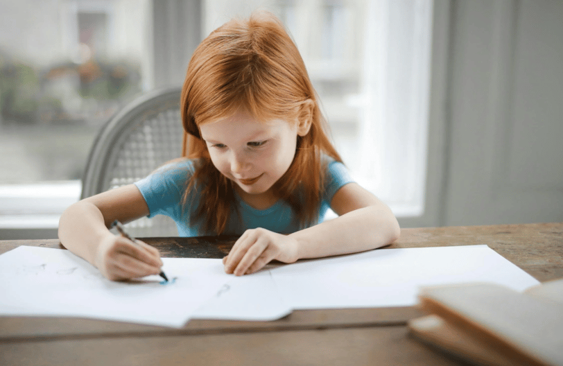A little girl draws and writes at home.