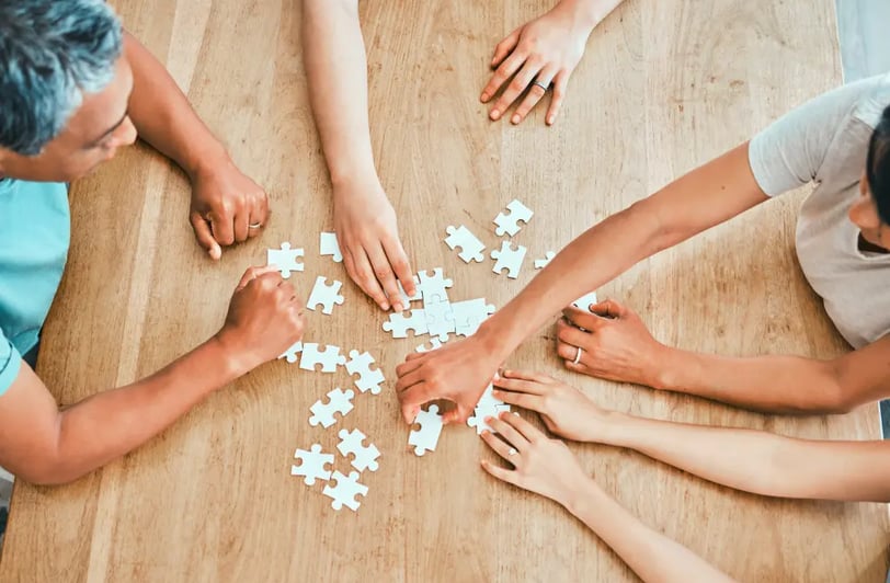 3 people solving a puzzle on a table