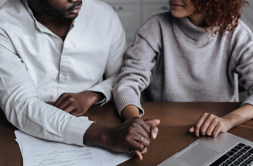 a man and woman sitting at a table with papers