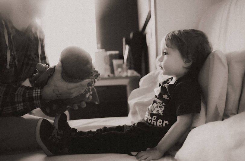 Big Brother getting ready to hold baby brother for the first time