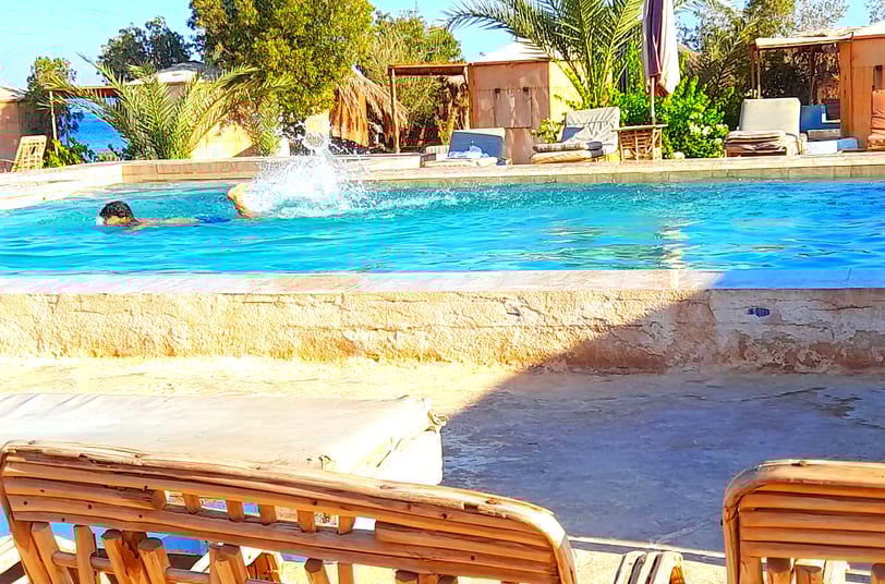 Băiat înot în piscină lângă mare și bungalou la starul beduin Egipt
