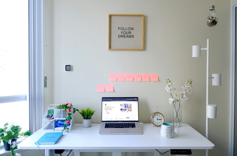 a laptop computer sitting on a desk with a note pad attached to it